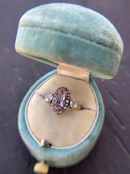 Elongated oval pink topaz with OMC side stones and an old swiss cut 20 stone halo ring in a teal velvet ring box. 